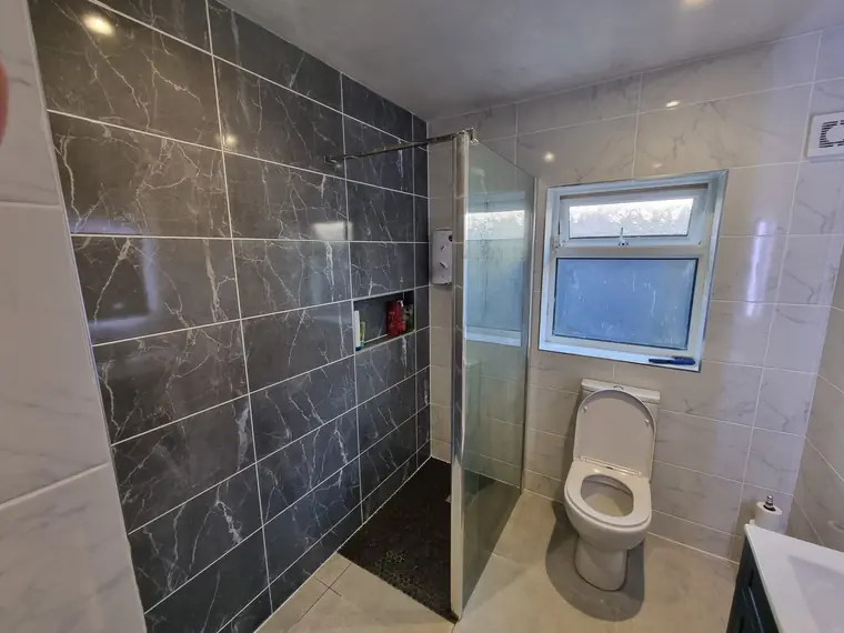 Bathroom with dark marble-effect wall tiles and walk-in shower, Bandon