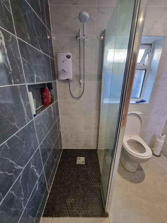 Dark tiled shower with recessed shelf niche and glass screen, Cork