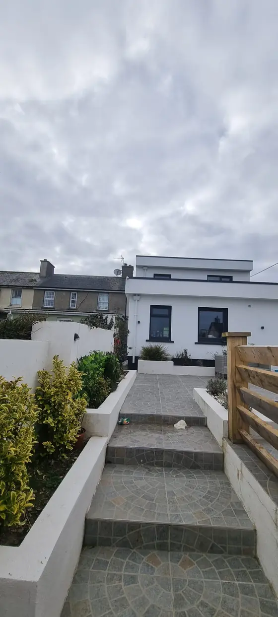 Modern white rendered extension with garden steps and paving, Cork